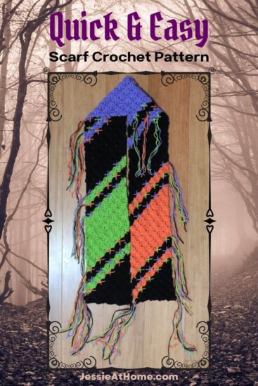 A vertical rectangular sienna image of a spooky forest. Over most of the image is a black decorative rectangular frame with a image inside of a corner to corner crochet scarf with diagonal lines of black, green, purple, and orange, with stitches at the color changes, laying on a wood floor. Above the frame is text "Quick & Easy" and "scarf crochet pattern". Below the frame is text "Jessie At Home dot com."